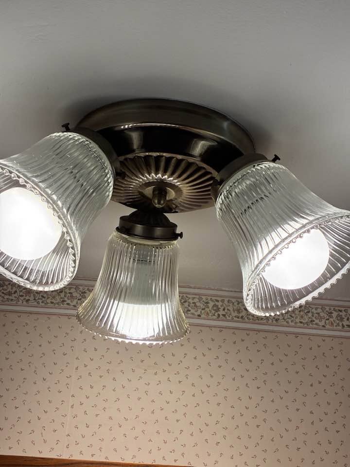 Clean three-shade ribbed glass ceiling light above a floral wallpaper border