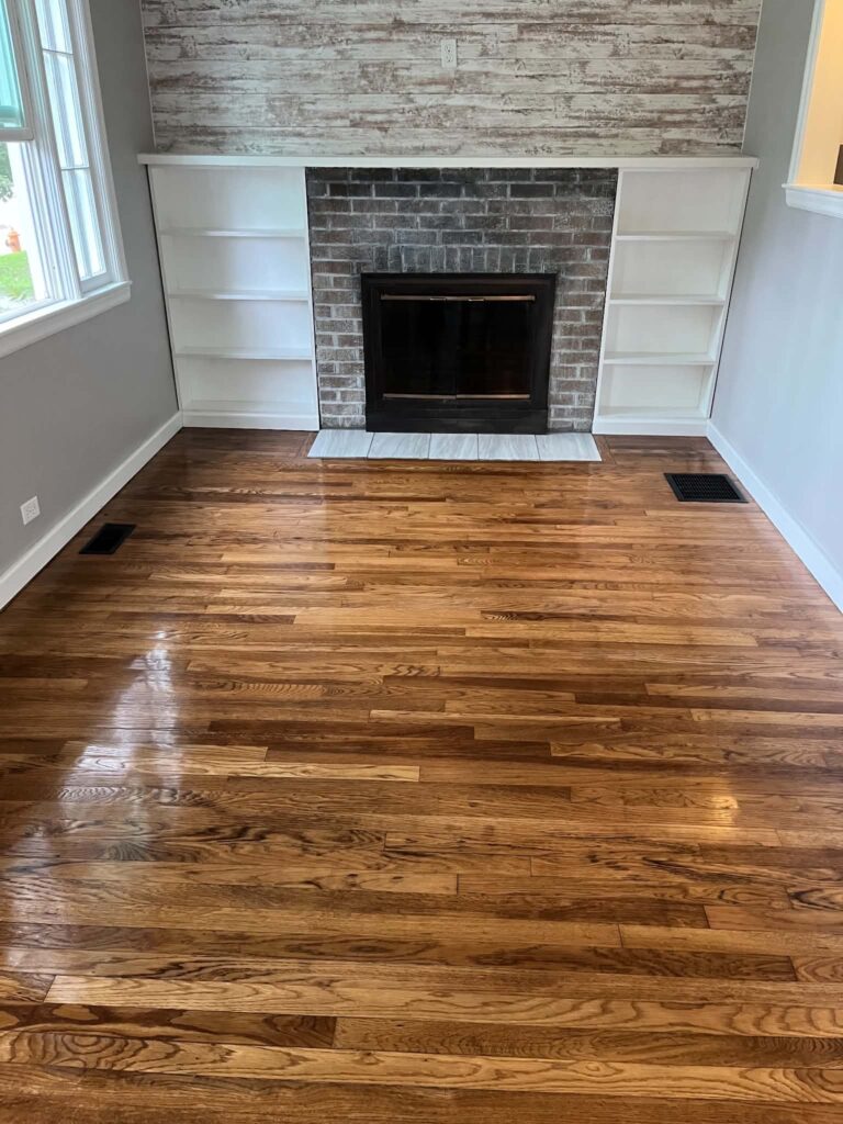 Glossy hardwood floor with a brick fireplace and white built-in shelves